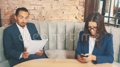 两个商人在一家咖啡馆工作。 人们正在专心地学习文件，然后把它们<strong>扔到</strong>桌<strong>子上</strong>。 女人是